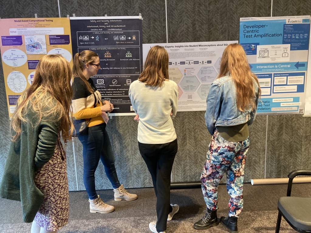 A photo of me in front of my poster, talking to some attendees.