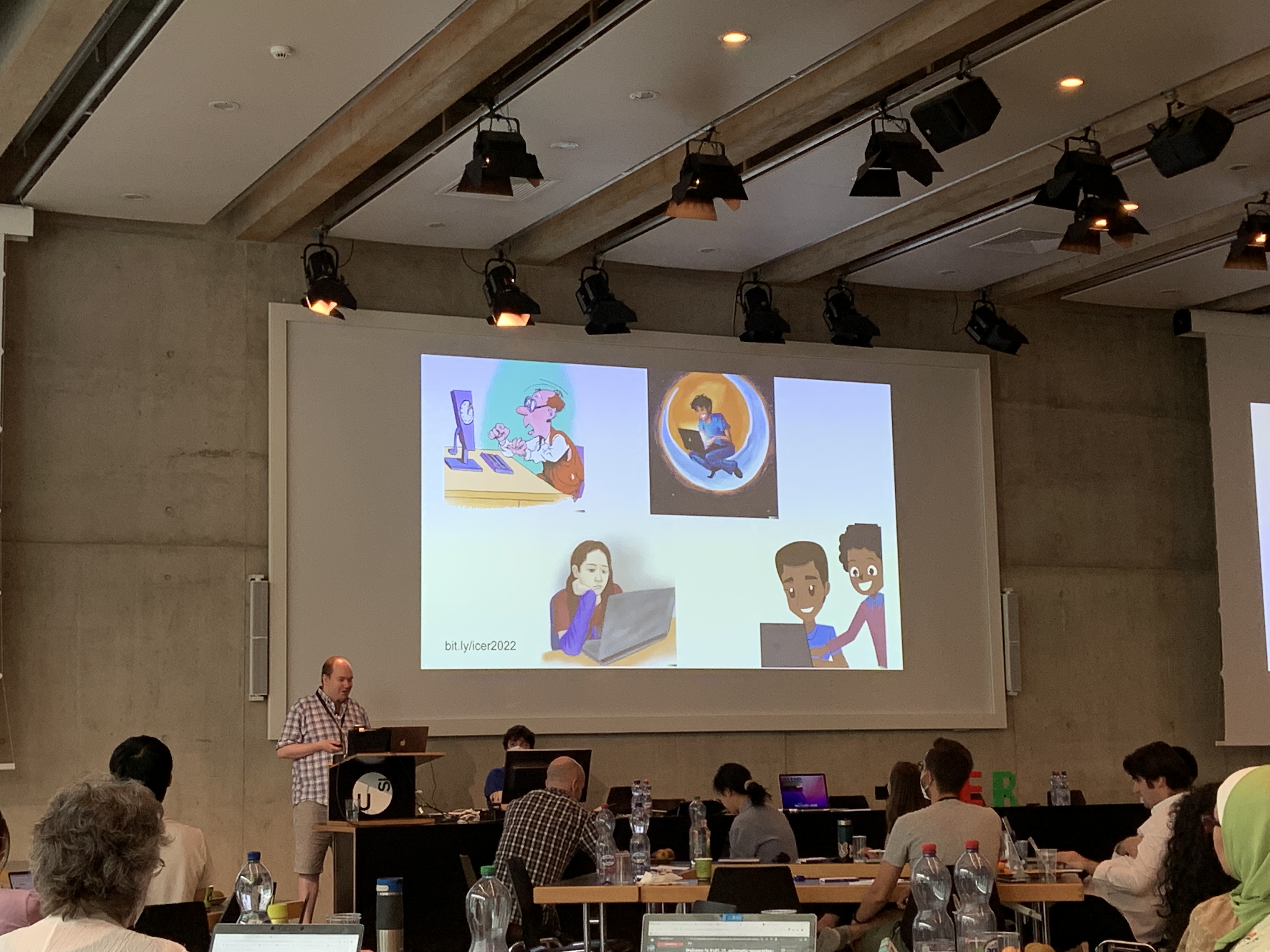 Juho Leinonen presents his work at ICER, standing in front of a large screen displaying examples of autogenerated images.