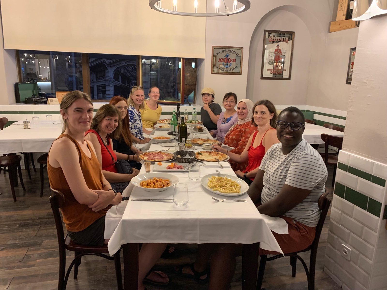 Ten happy ICER participants sitting around a rectangular table, eating pizza or pasta.