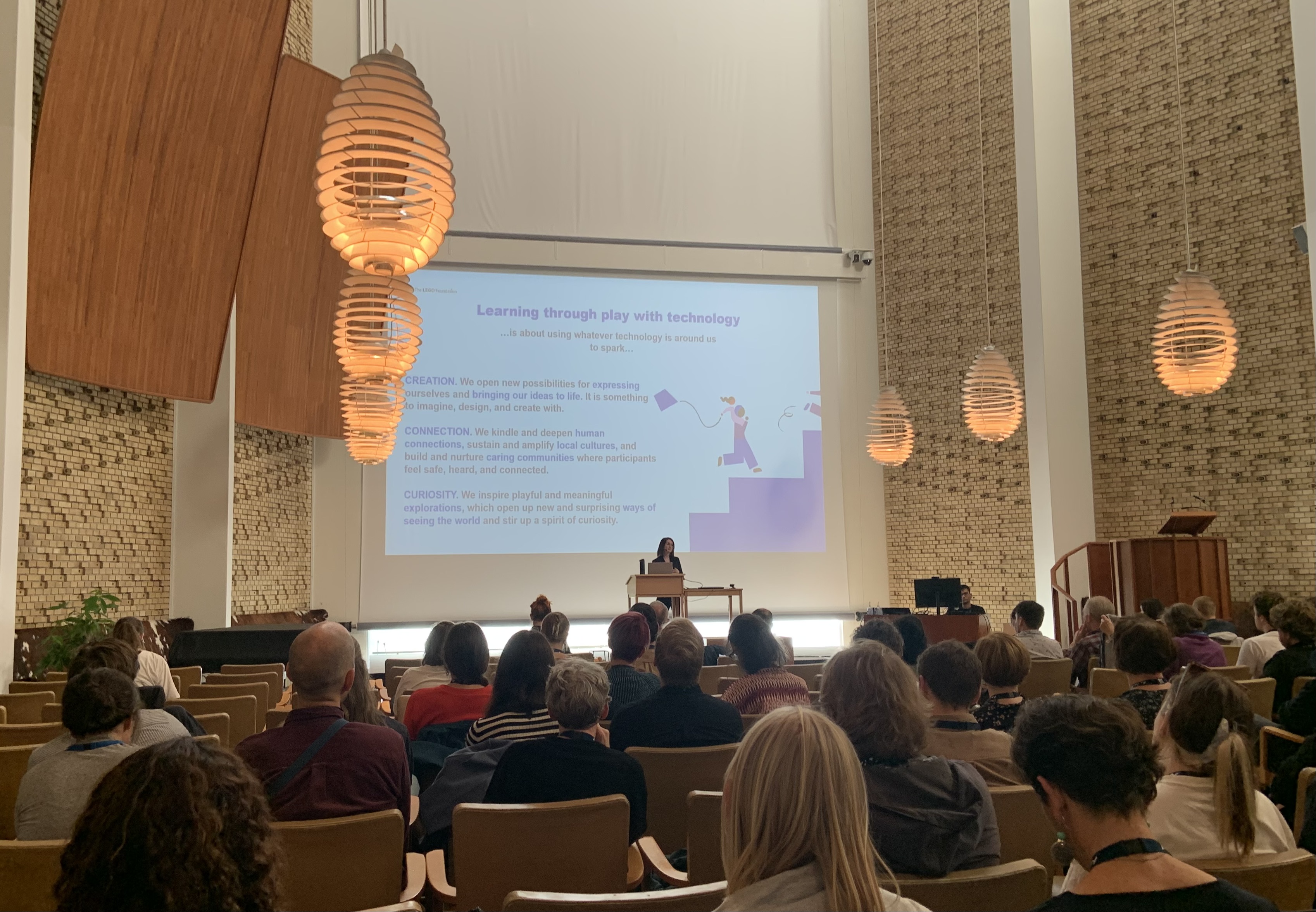 Elisabeth on stage in the Aarhus University aula, presenting learning through play with technology.