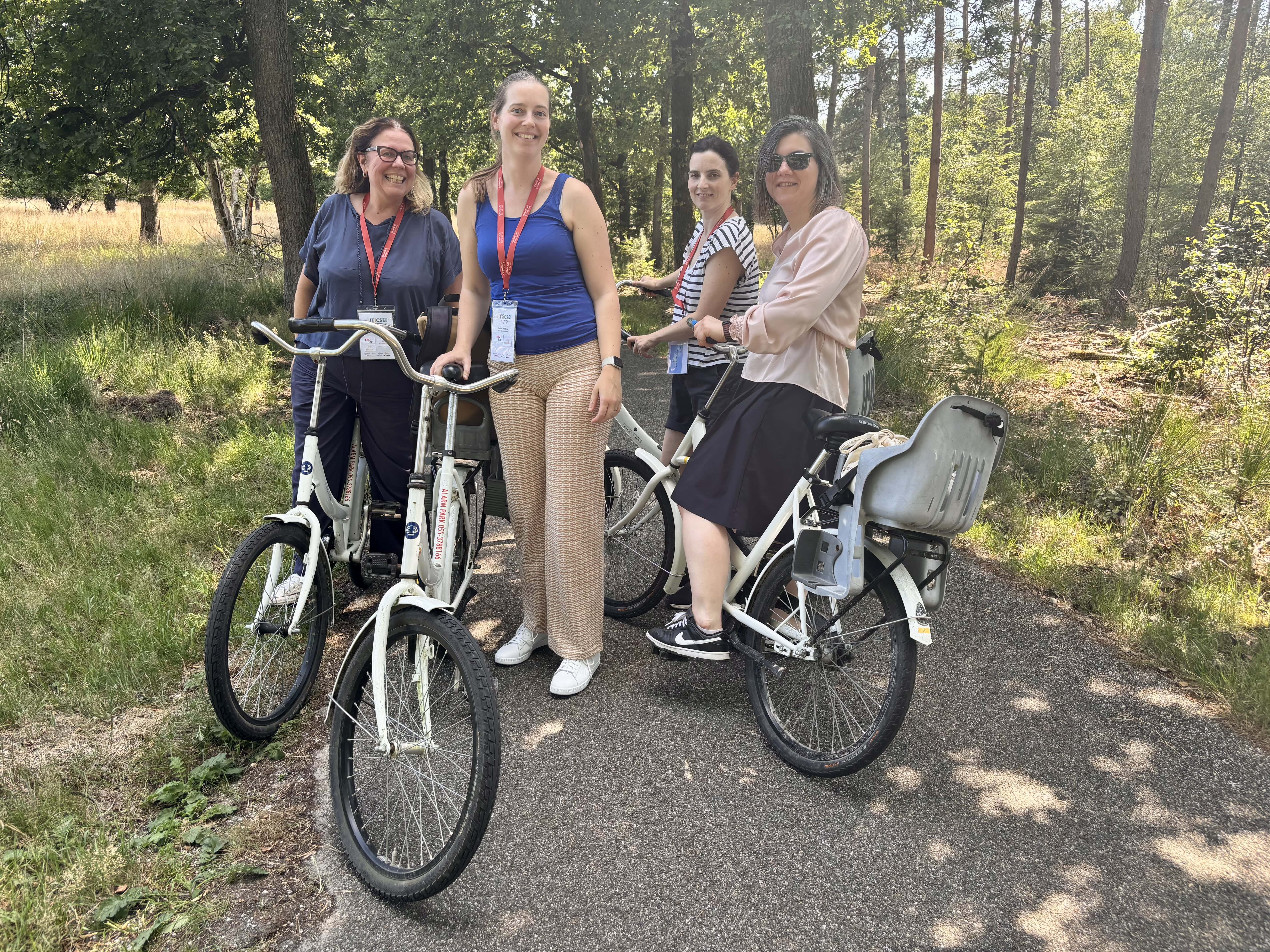 A picture of four people on or near bikes, with a grassy background. 