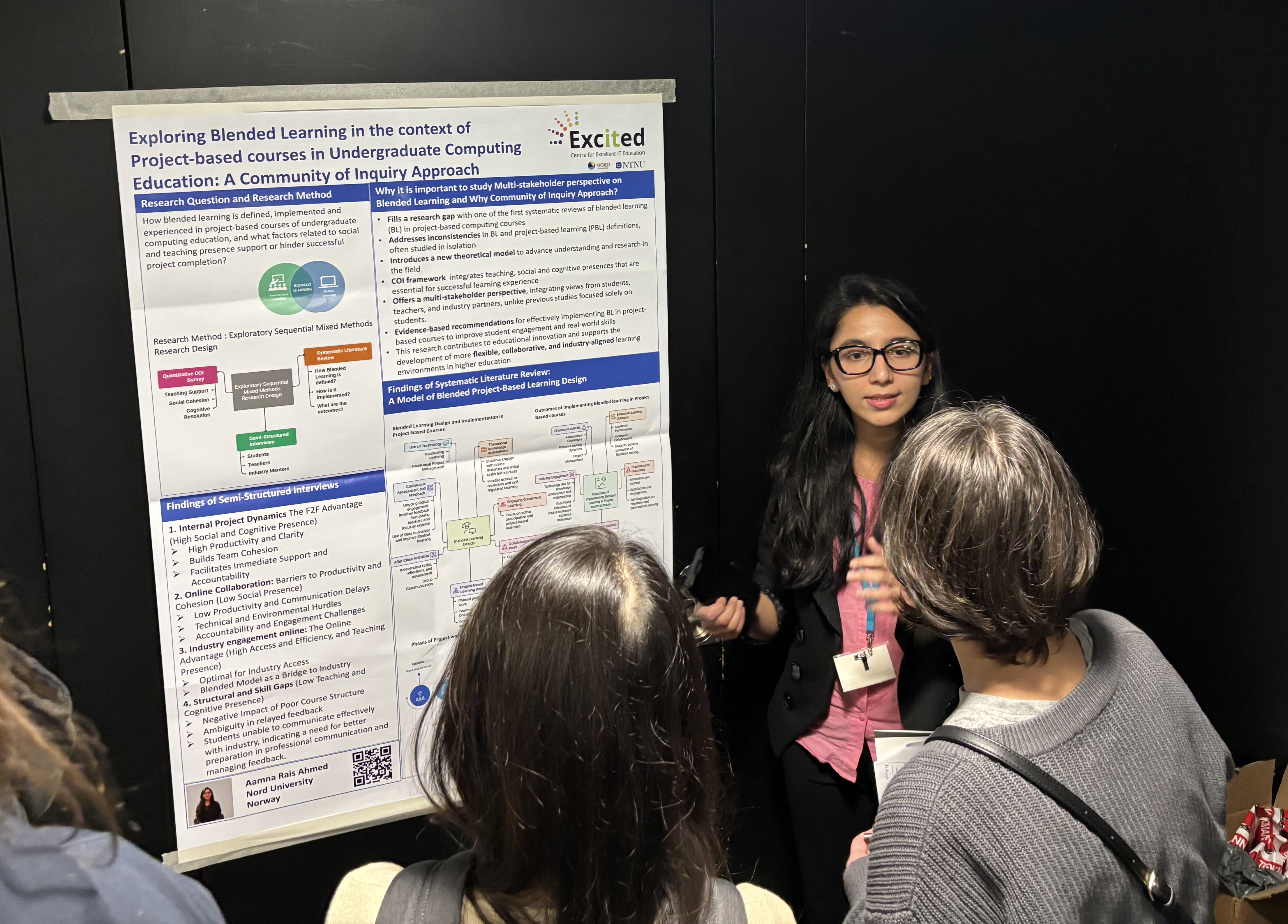 A picture from the poster session. On the left-hand side there is a poster on blended learning for project-based courses, on the right-hand side Aamna is presenting. There are two people watching, of whom you can only see the back of their heads.