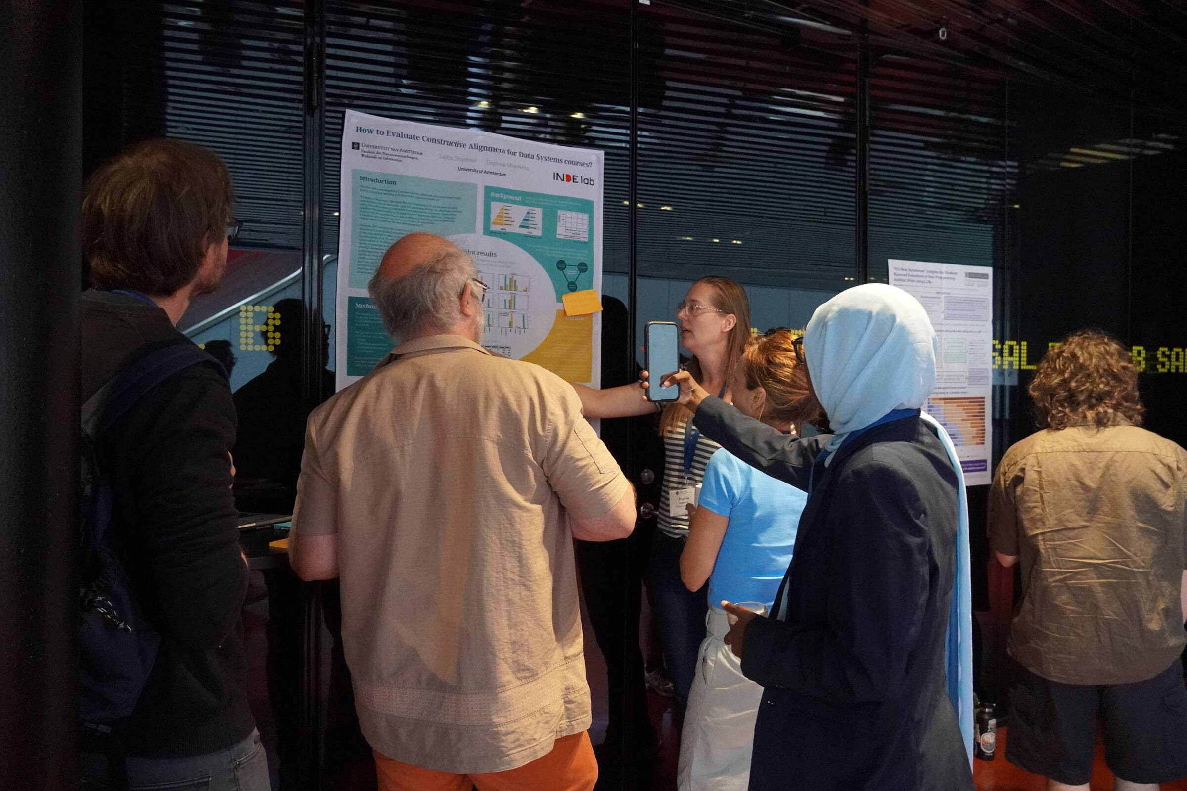 Me presenting my poster, discussing elements with attendees, while another attendee is taking pictures of the contents.